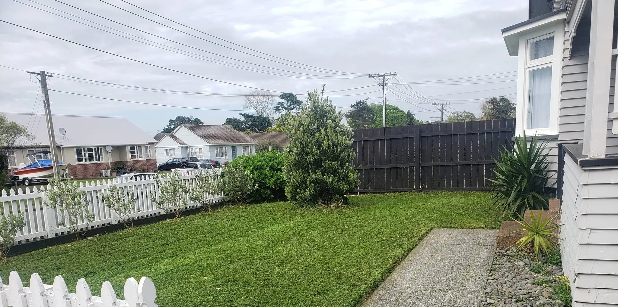 A freshly mown front lawn behind a white picket fence, edged along the path by 0-Nine Lawn Care